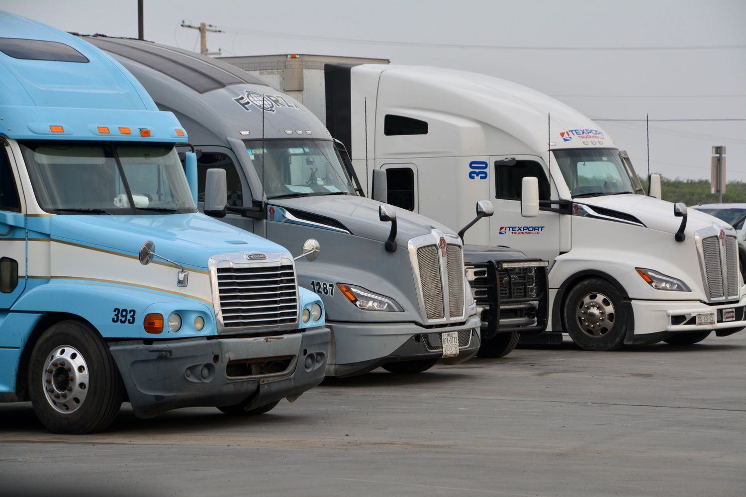 A row of tractor units parked in a Texas truck yard between runs